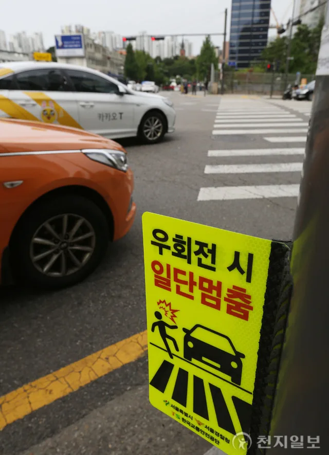 Taxis at a right-turn crosswalk beside a "Stop before turning right" sign in Seoul. Photo: Cheonji Ilbo