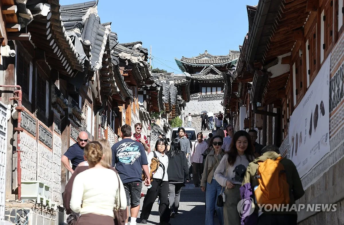 Tourists walk up a narrow lane lined with traditional hanok houses in Bukchon Hanok Village, Seoul. Photo: Yonhap News