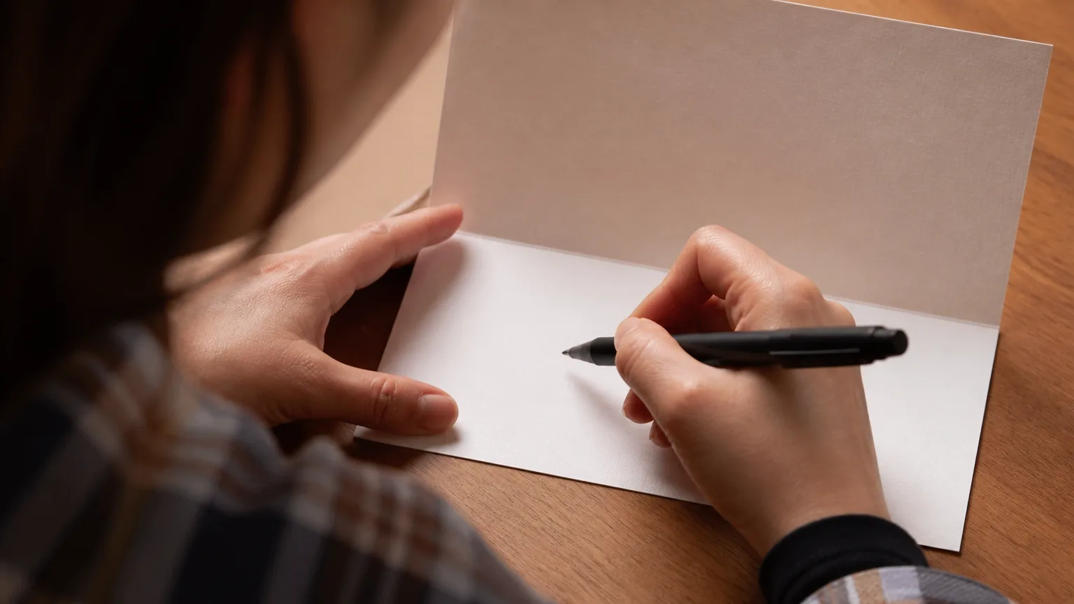 Person writing a name on a greeting card with a black pen