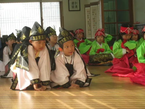 Students in hanbok practicing the traditional Korean bow (jeol), with hands clasped in gongsu posture. Photo: Naver News