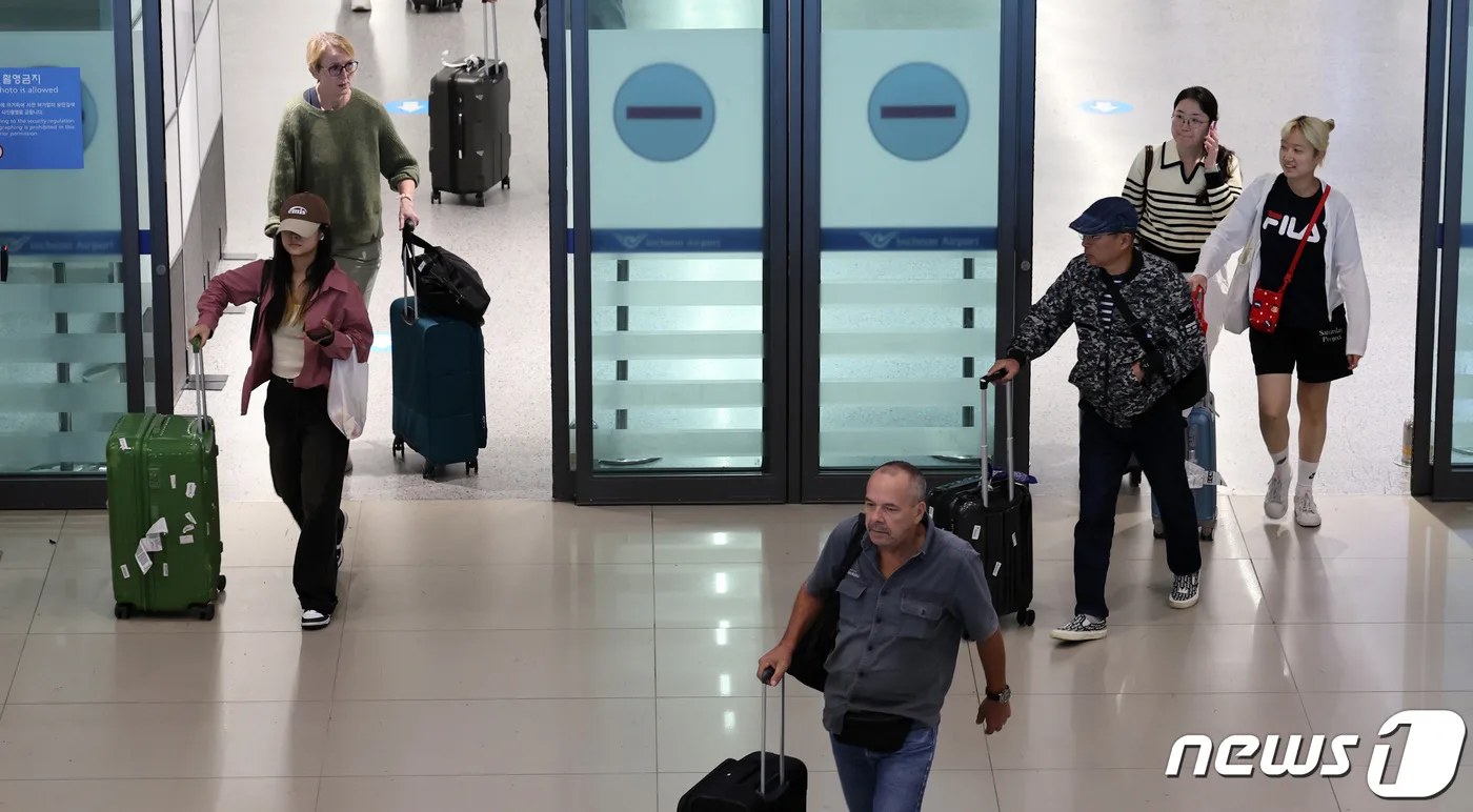 Travelers pulling suitcases through the arrivals doors at Incheon International Airport. Photo: News1